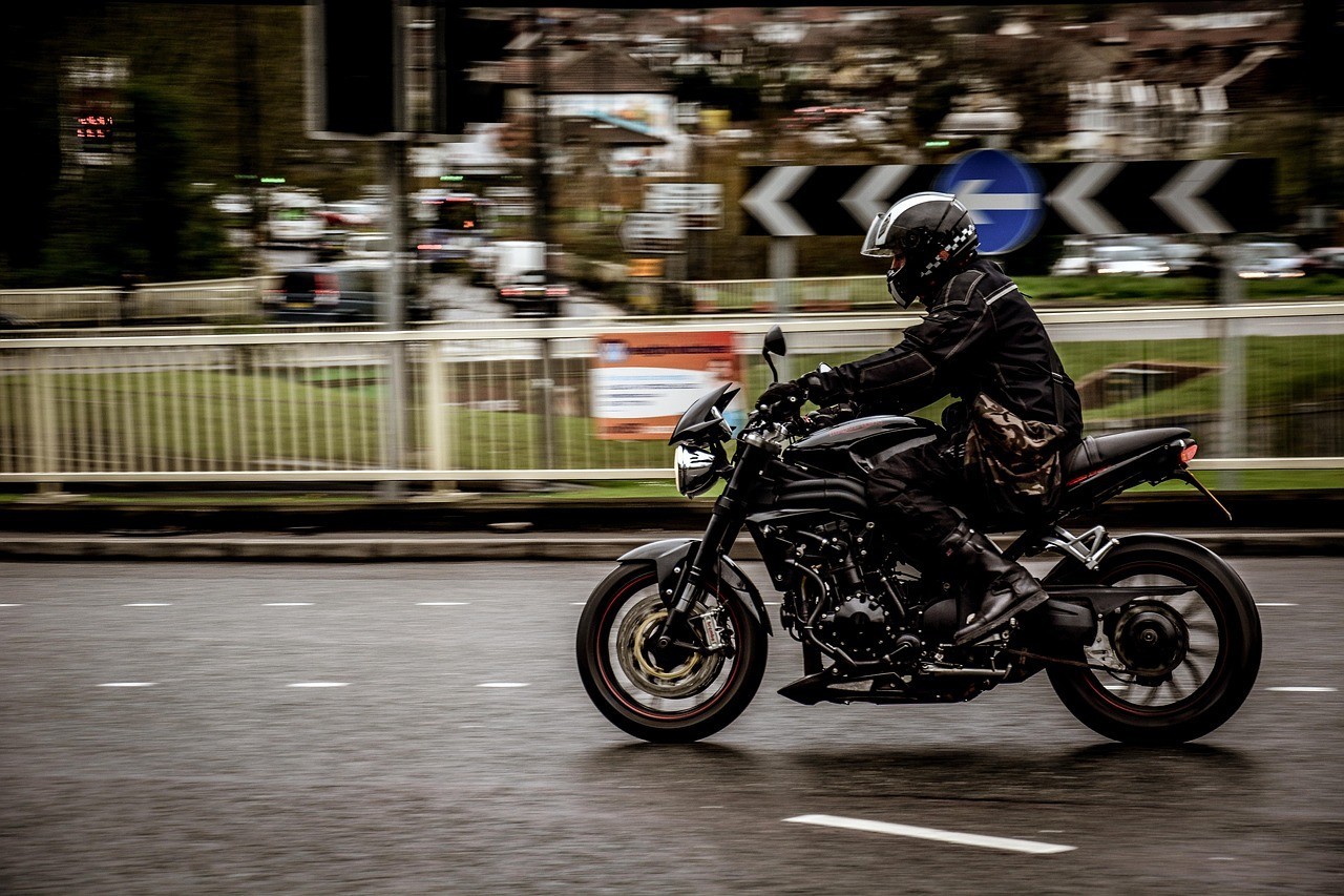 An in-motion image of a motorcyclist driving through a town.