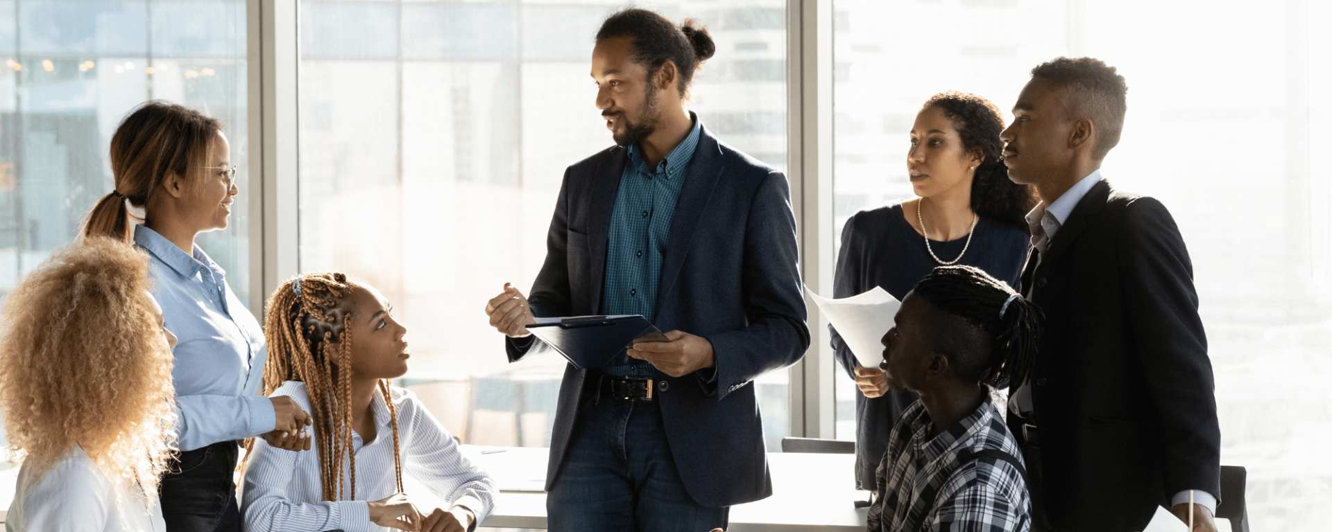 A small group of employees pay attention to their manager as he speaks.