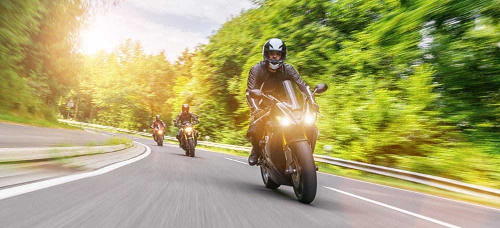 An in-motion image of a group of motorcyclists driving through scenic rural roads