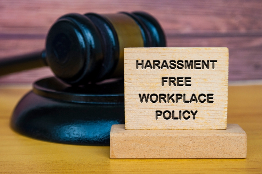 a judges hammer with a sign next to it saying "harassment free workplace policy"