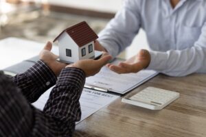 man passing a little house to another man