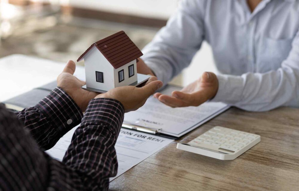 Rules of Intestacy Flowchart – What Happens If There’s No Will? A man passes a small wooden model of a house to another man