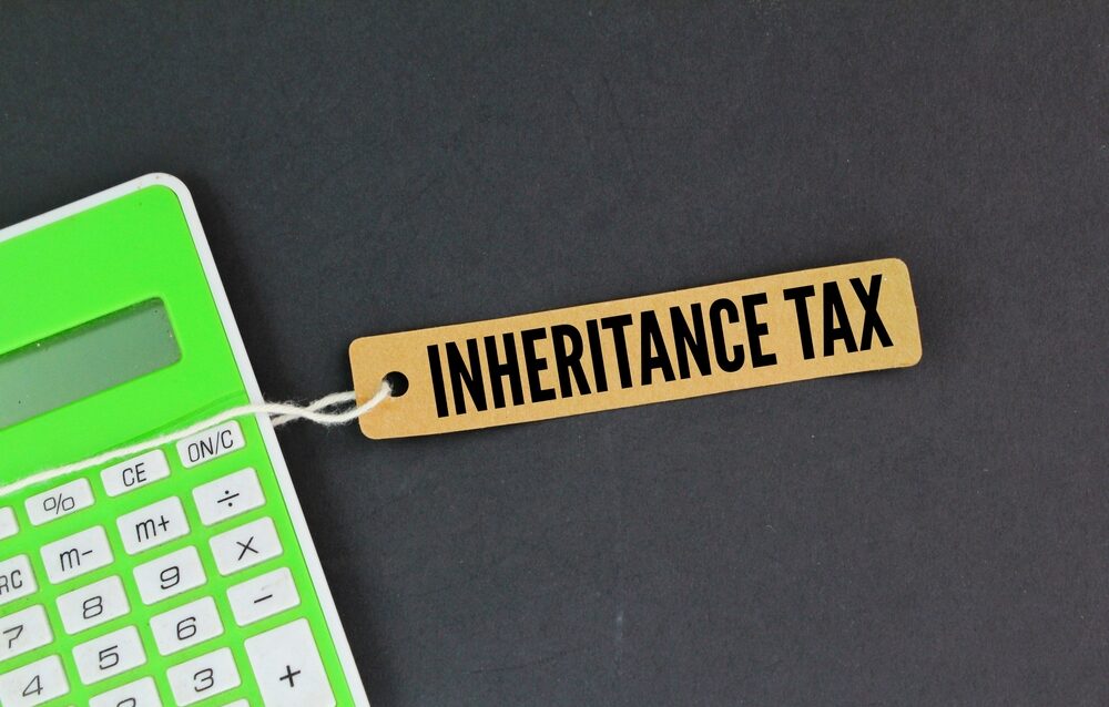 Inheritance Tax Calculations A green calculator with a tag saying inheritance tax attached to it on a gray background