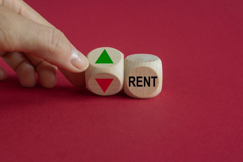 two dice, one says rent, the other had a green arrow pointing up on one side and an orange arrow pointing down on the other, signifying rent increase.