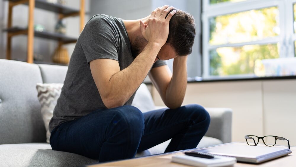 A person sitting on a couch with their head in their hands.