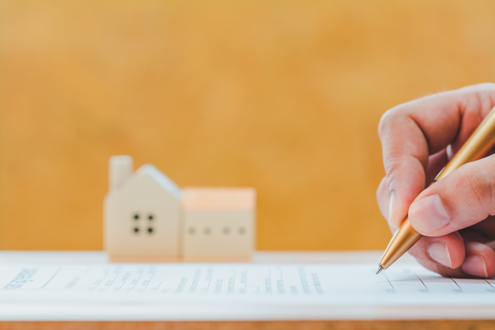 Document getting signed with a miniature house.