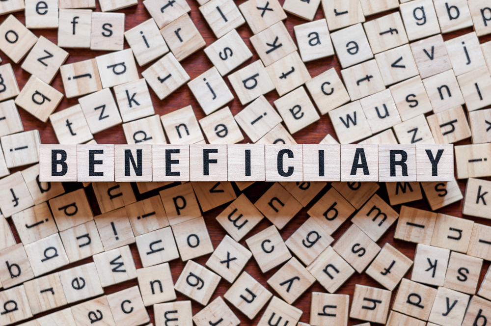 a bunch of scrable letters in the background with the blocks in the foreground spelling beneficiaries