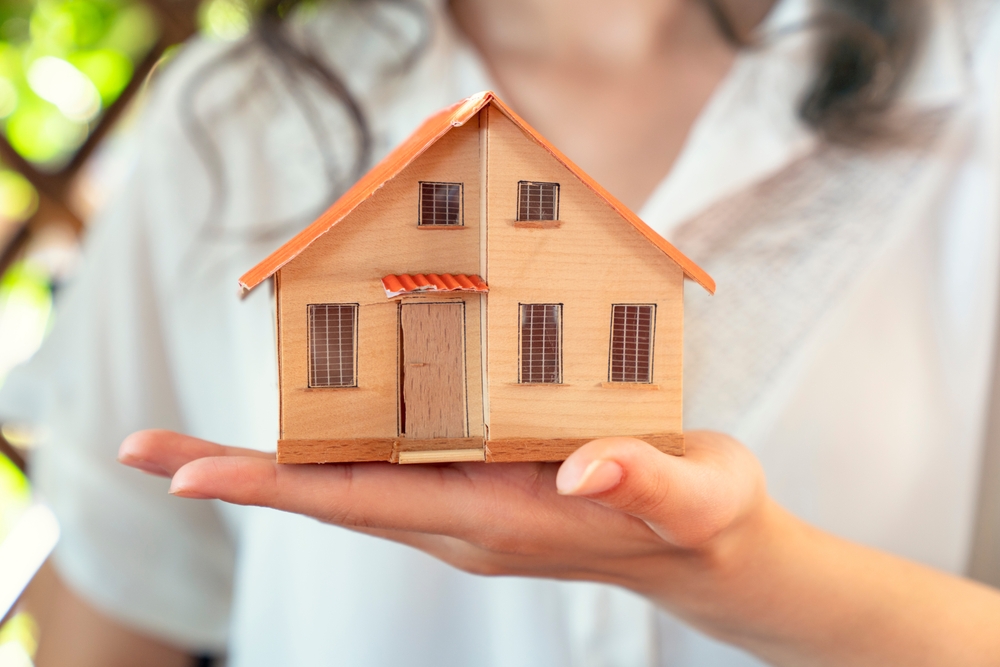a woman holding a little house in her hand to represent renting